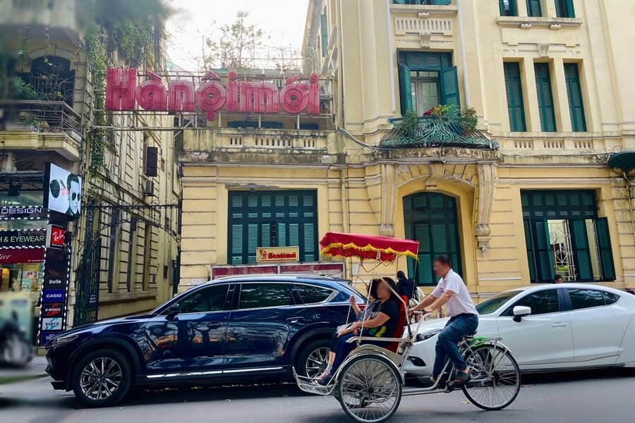 Ô tô và xích lô di chuyển trên đường phố khu phố cổ Hà Nội