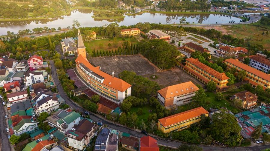 Aerial view of Da Lat Pedagogical College showcasing its iconic French-style red-brick building and curved architecture.