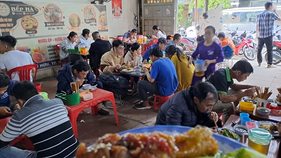 Busy Vietnamese street food stall with locals enjoying meals