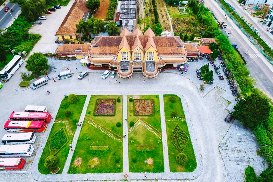 Parking area with private cars and tourist buses in front of Da Lat Old Train Station during sightseeing trips.