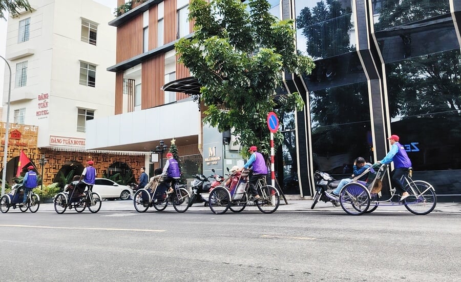 Cyclo carrying tourists through a street in Hue, a popular experience-focused city transport option in Vietnam.