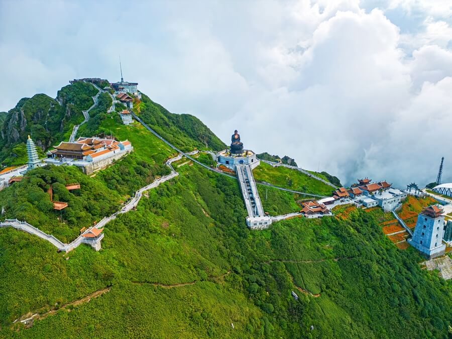 Fansipan mountain peak with clouds, forest, temple, and statue in northern Vietnam