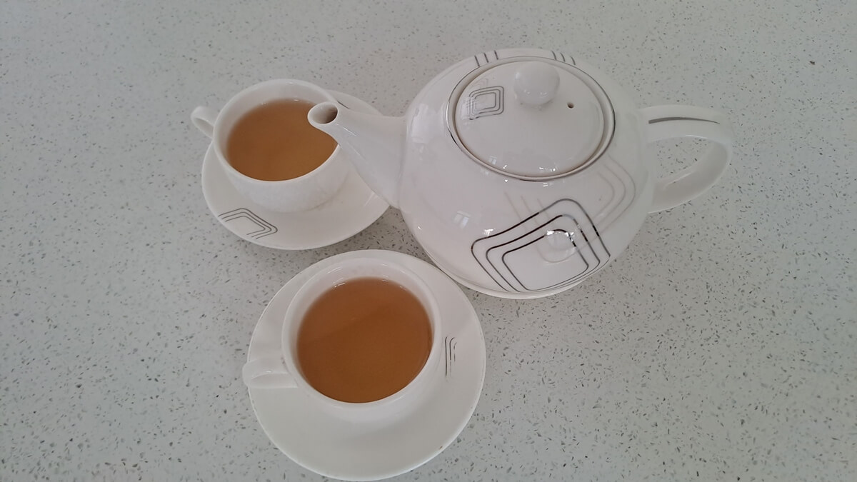 Vietnamese tea pot with two cups of hot yellow tea
