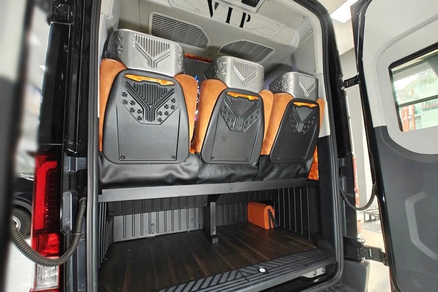 Rear view of a Dcar Limousine van showing a spacious luggage area with premium leather VIP seats and a clean wood floor for secure storage