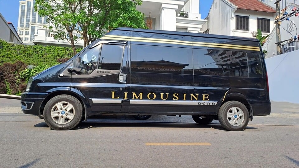 ide view of a black DCar Limousine Ford Transit with large gold LIMOUSINE lettering and high roof, ideal for VIP group transport in Vietnam