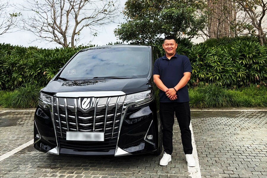 Professional chauffeur standing next to rental car for long-term car rental service