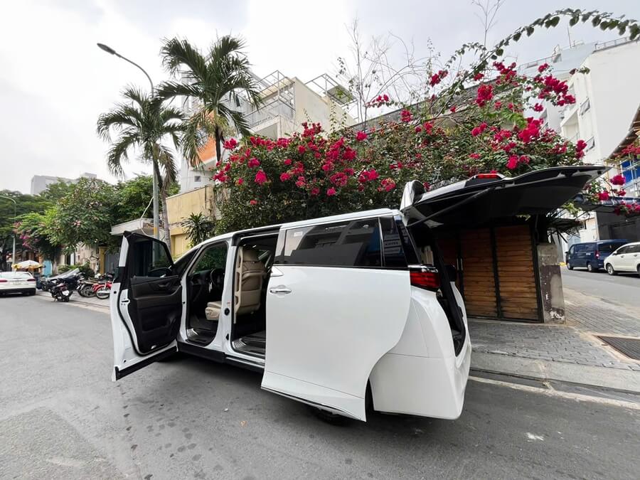 White Toyota Alphard luxury MPV with open doors on a street in Ho Chi Minh City, Vietnam