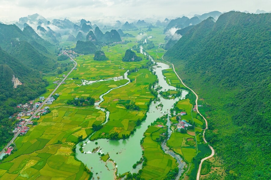 Two roads running along a village in a valley surrounded by limestone mountains in Northern Vietnam