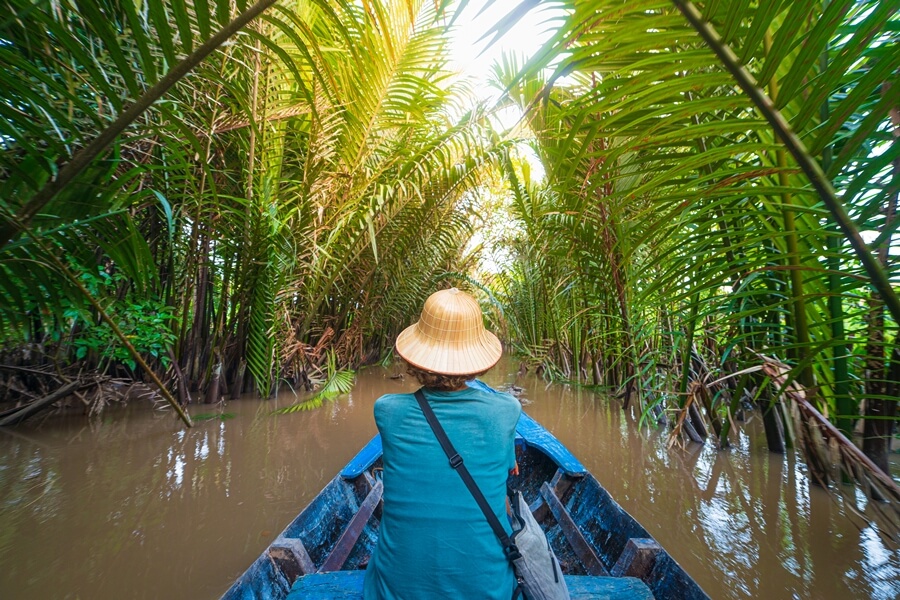 Boat ride through a narrow canal lined with coconut trees in My Tho, Mekong Delta
