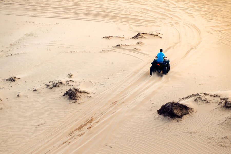 riding a quad bike across the sand dunes in Mui Ne during the late afternoon