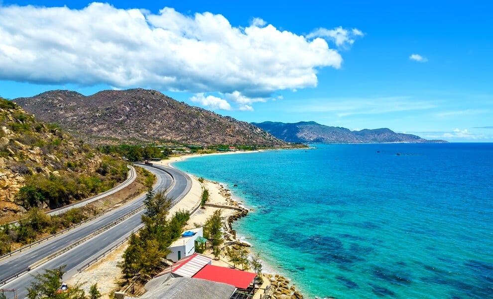 The winding coastal road through Ca Na, with rocky hills and the deep blue sea, on the journey from Nha Trang to Ho Chi Minh City via Mui Ne