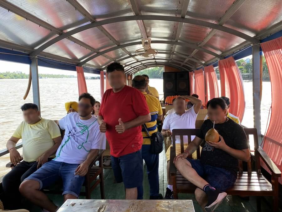 Visitors enjoying fresh coconut water during a boat trip through the waterways of Ben Tre